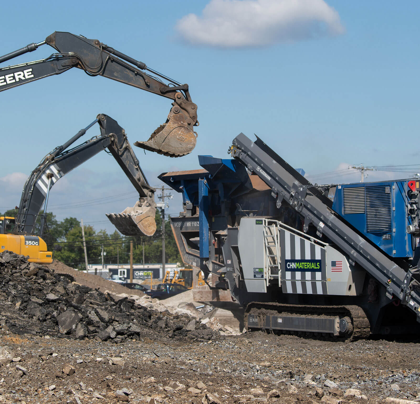 Two excavators transferring crushed material to a CH+N Materials truck for recycling